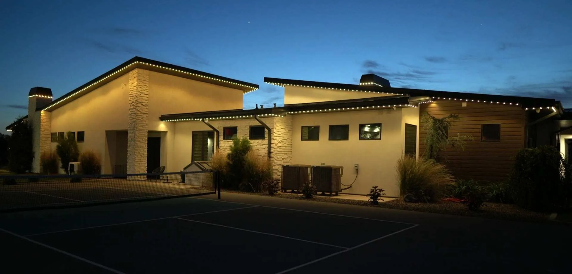 Home with warm white accent lighting outlining the roofline at dusk