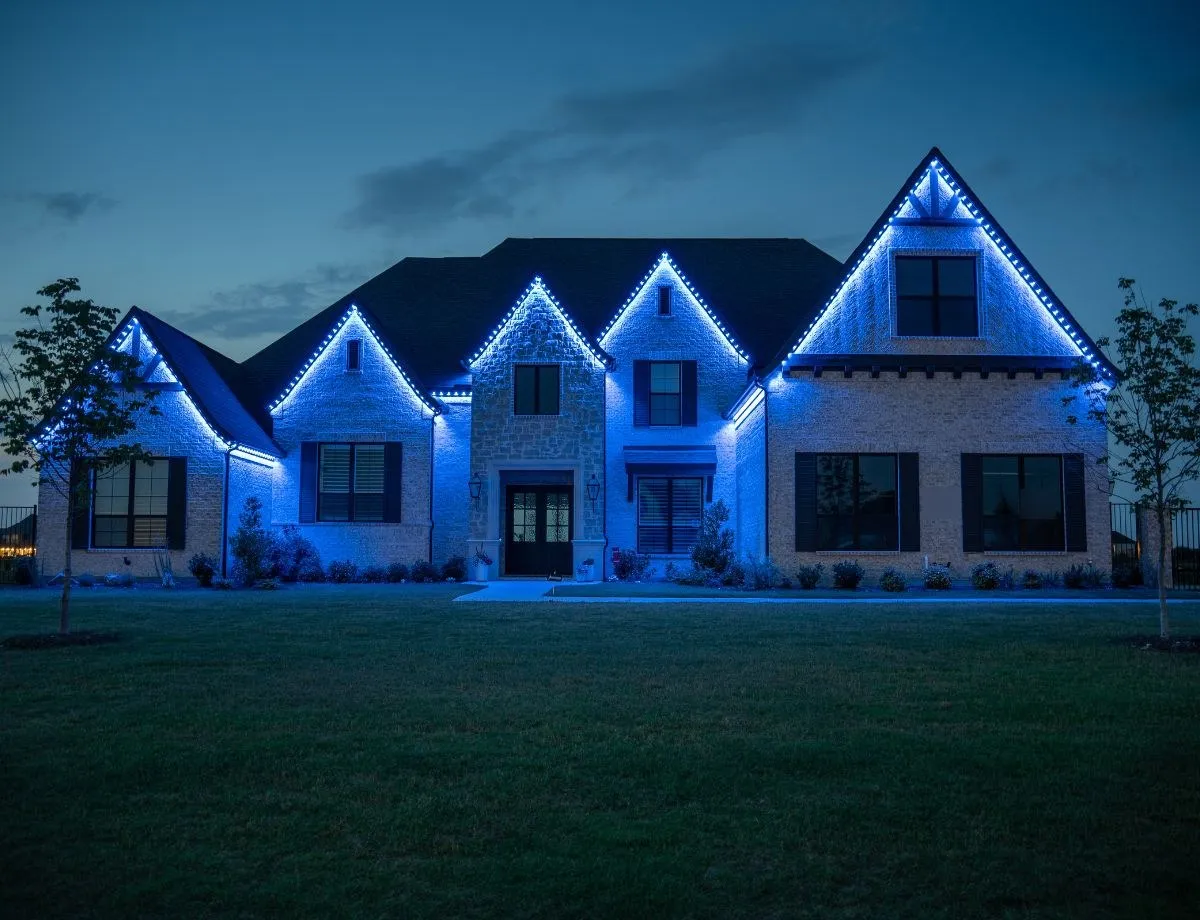 Stone home with five gables lit in blue for game day