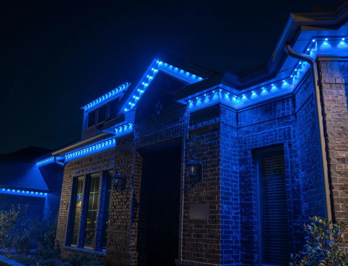 Brick corner of a home with deep blue roofline lights