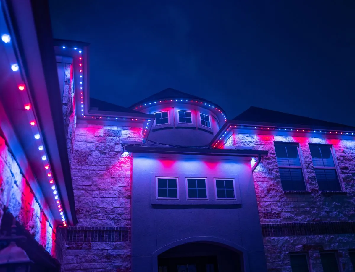 Red, blue and white lights along the eaves of a stone home