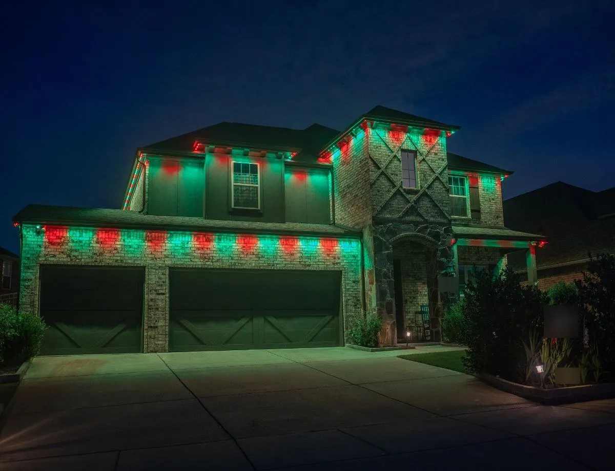Two-story home with red and green holiday lights over the garage